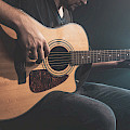 © pvproductions | freepik.com | (Close-up of a man playing an acoustic guitar in the dark with stage lighting)