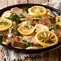© FomaA | stock.adobe.com | (Scaloppini tender veal cooked with mushrooms and lemons in a spicy sauce close-up in a frying pan on the table. horizontal)